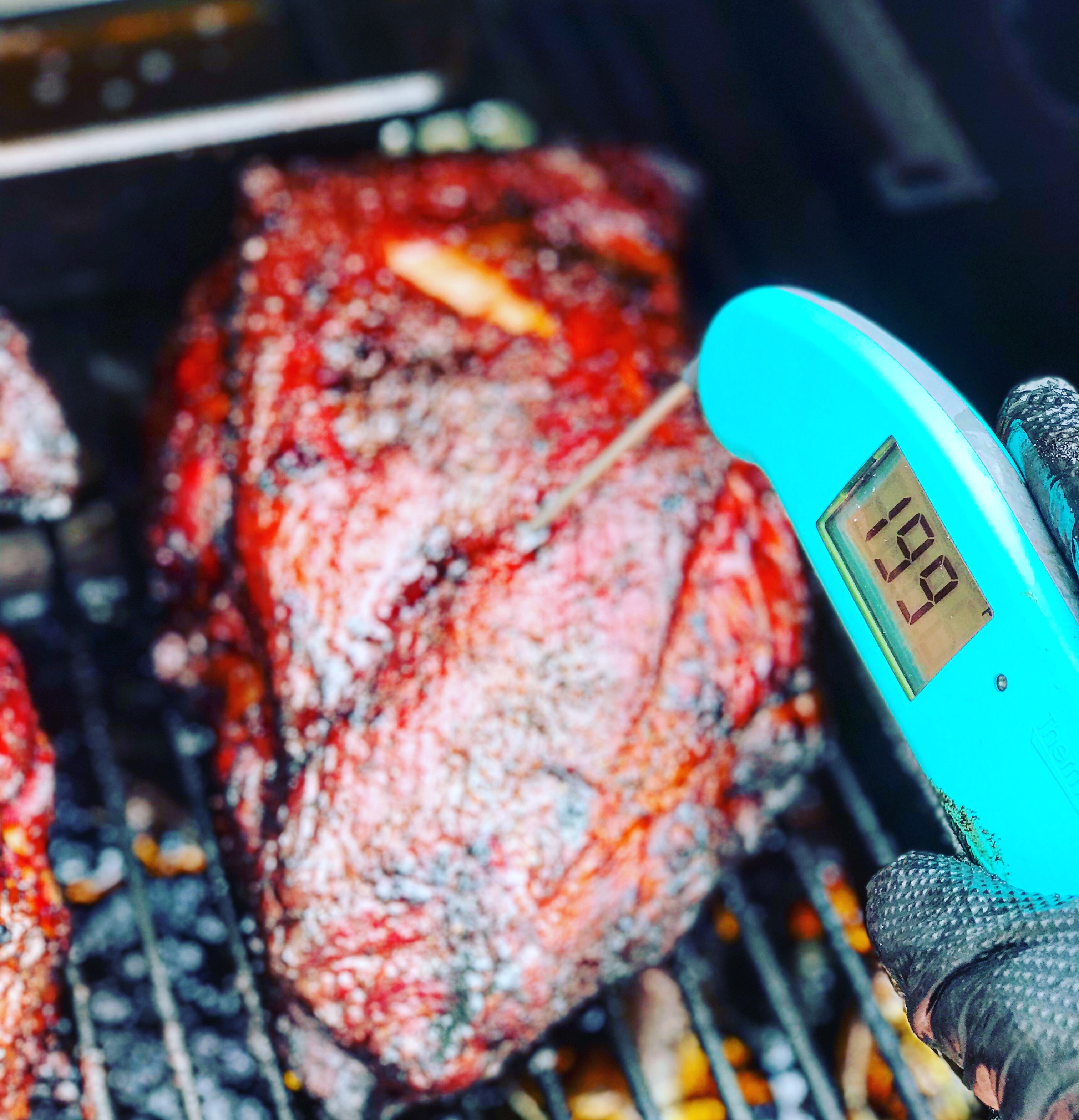 Monitoring temps of the smoked pulled pork with a digital thermometer.