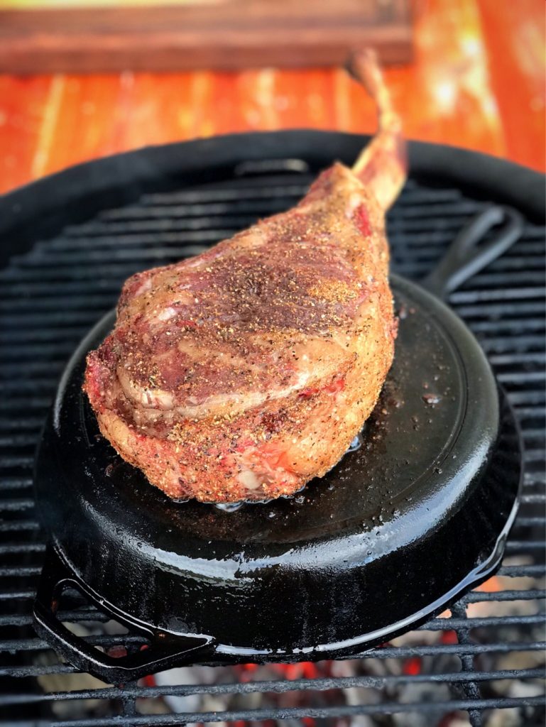 Tomahawk ribeye getting reverse seared on the back of a cast iron skillet.