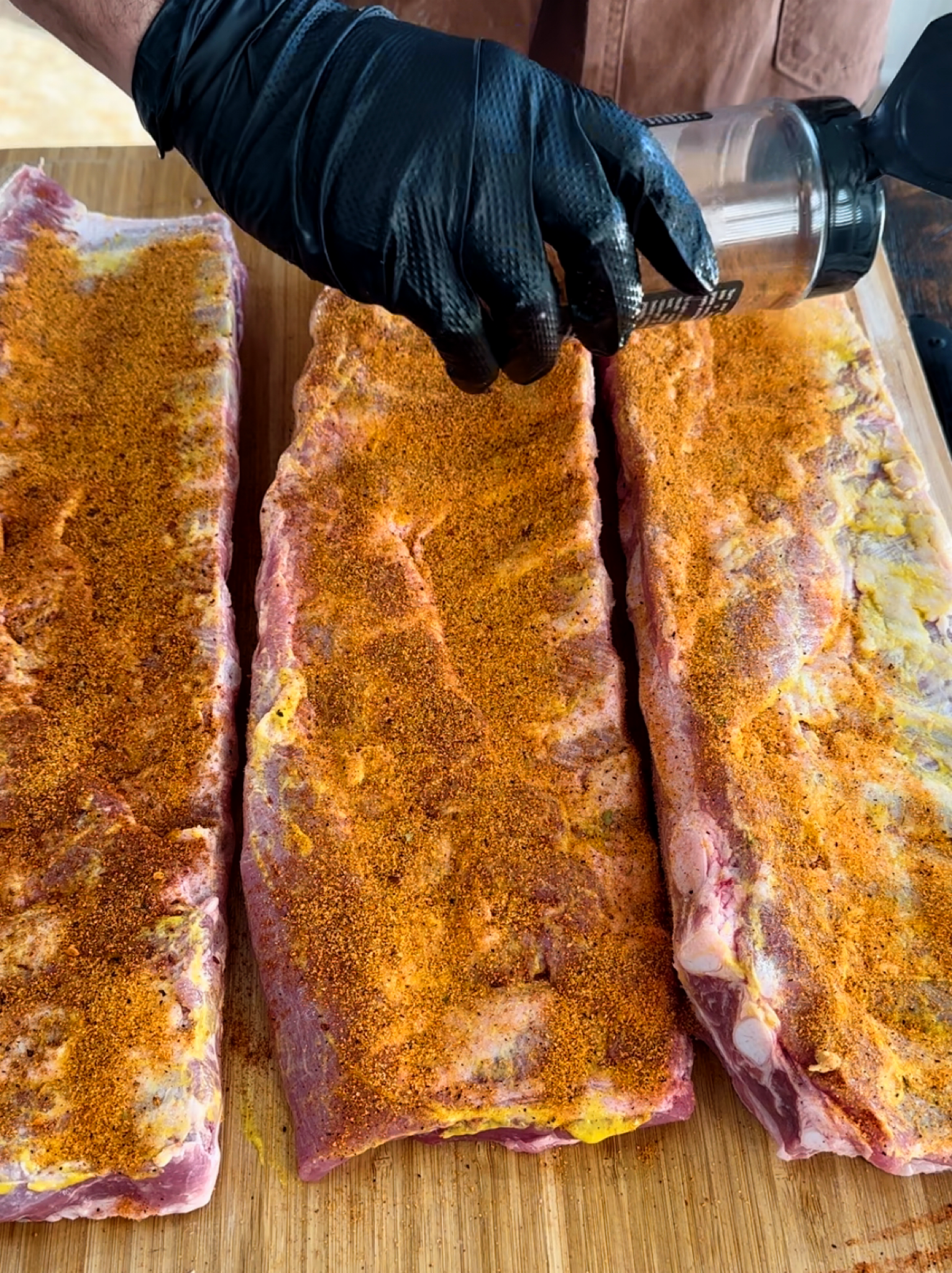 St. Louis style ribs being prepped with mustard and seasoning. 